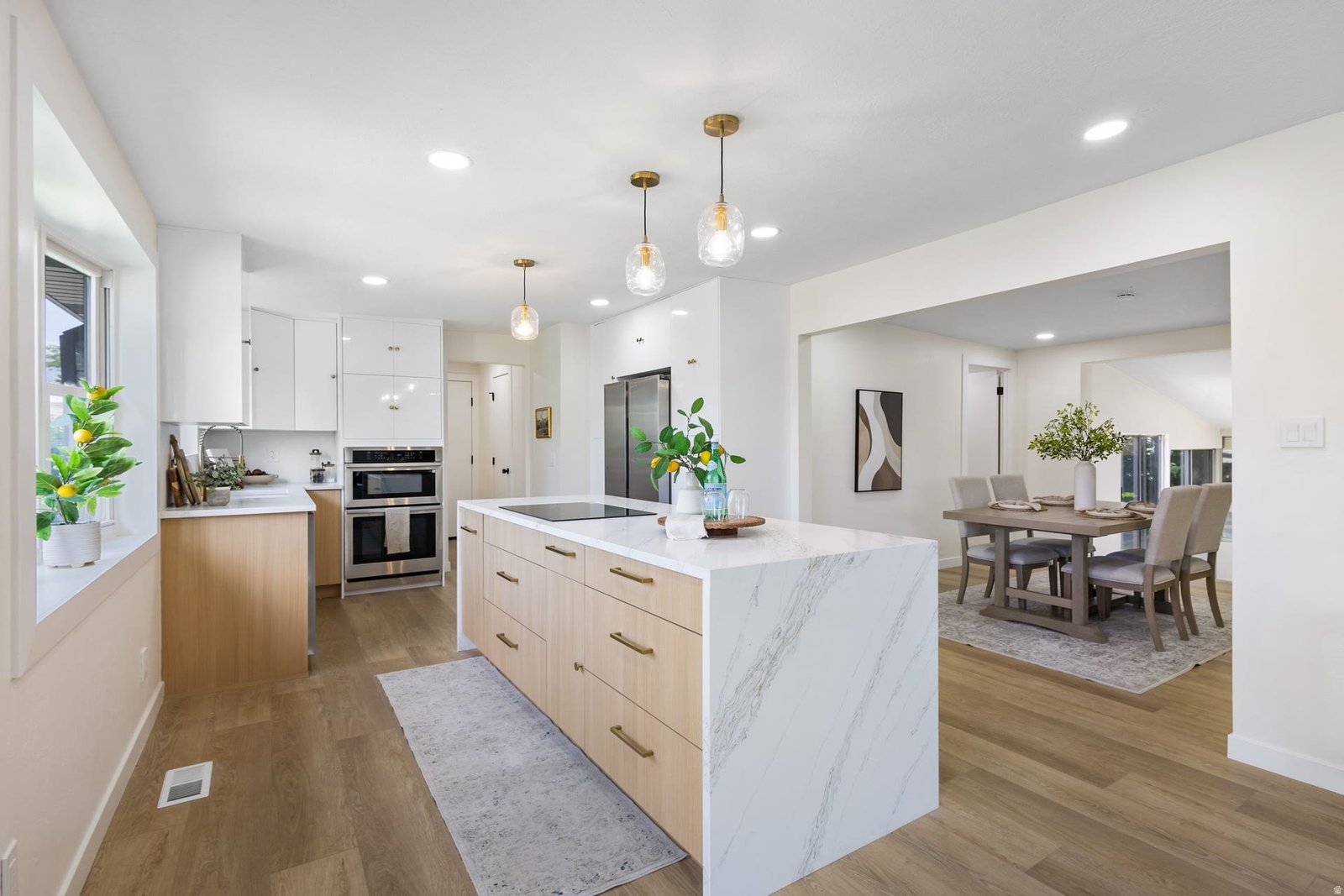 Kitchen Remodeling Utah County — White Kitchen With Wood Island and Marble Countertop Bright white kitchen remodel with wood island, marble waterfall countertop and open dining area in Utah County